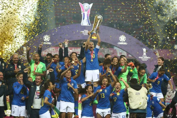 Women's Brazil players picking up the Women's Copa America after their 2022 win