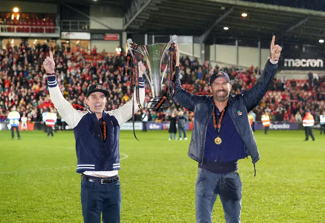 Ryan Reynolds and Rob McElheney holding the cup their team, Wrexham, won by becoming National League champions