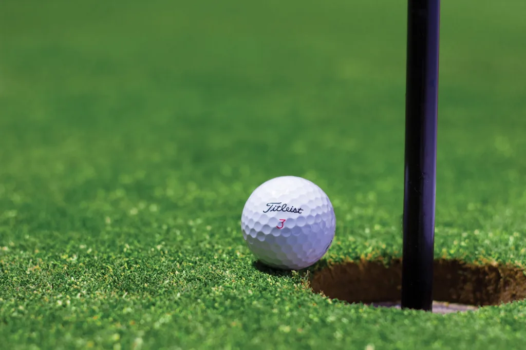 A golf ball, on of the Essential Golf Accessories, almost entering the hole