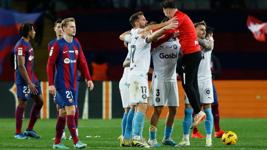 Girona FC players celebrating their victory against FC Barcelona with the Barca players looking disappointed