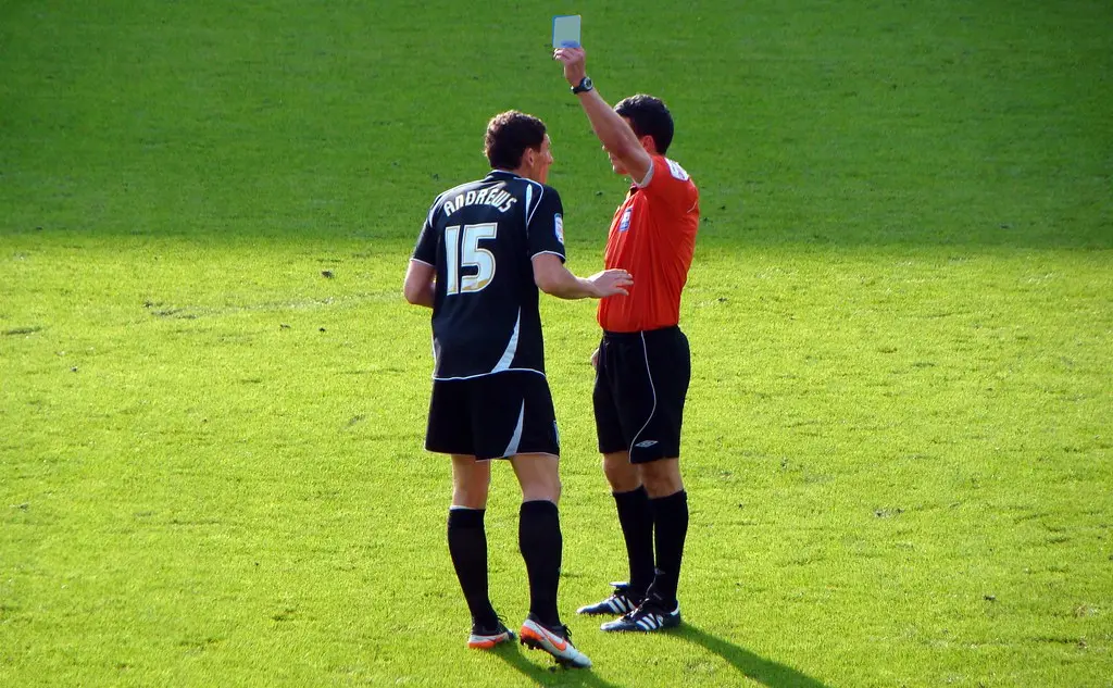 A referee giving a player a blue cards